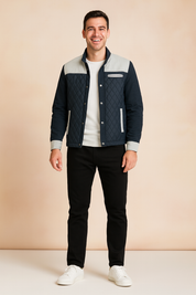 Navy blue quilted jacket with light gray shoulder panels and trim, styled with black trousers and white sneakers.