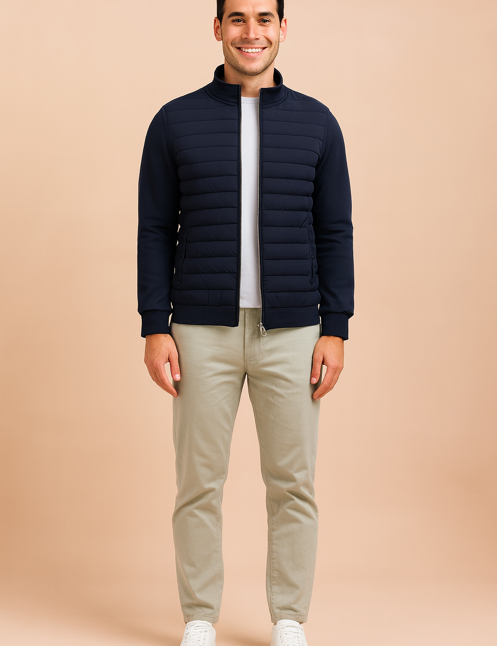 Navy blue quilted zip-up jacket with ribbed cuffs, horizontal padded front detailing, and side pockets, styled over a white shirt and paired with light trousers.