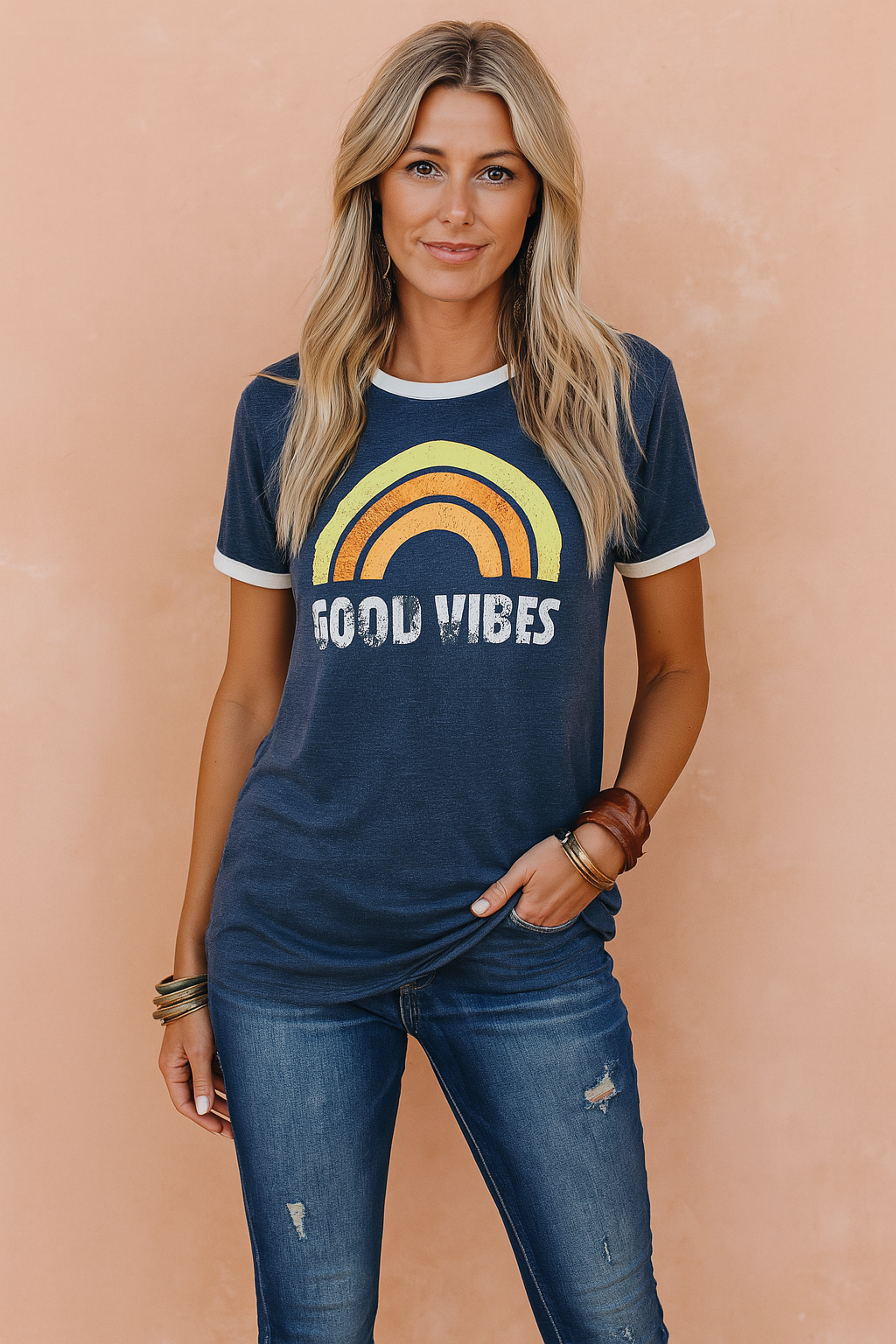Vintage-inspired navy blue graphic tee featuring a retro rainbow print and distressed "Good Vibes" lettering, paired with medium-wash ripped skinny jeans for a laid-back, boho-chic casual look.