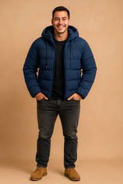 Men's navy blue puffer jacket with hood, black t-shirt, dark gray jeans, and tan suede boots