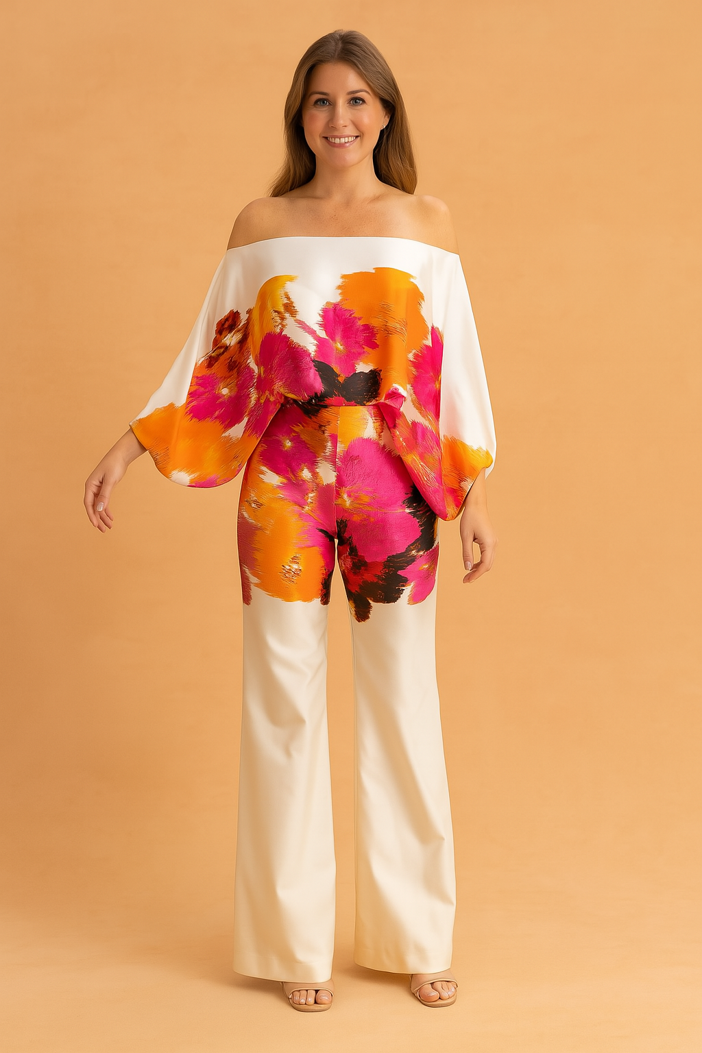 Vibrant off-shoulder two-piece set featuring a flowing wide-sleeve top and high-waisted cream trousers, detailed with bold orange, pink, and black abstract floral prints on silky fabric.