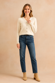 Off-white V-neck button-up cardigan with long sleeves, paired with medium-wash straight-leg jeans and tan suede ankle boots.