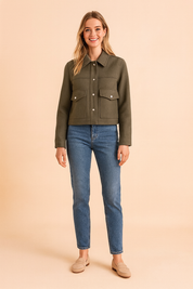 Olive green cropped jacket with front button closure, structured collar, and dual flap chest pockets, styled with classic straight-leg denim jeans and beige loafers for a casual chic look.