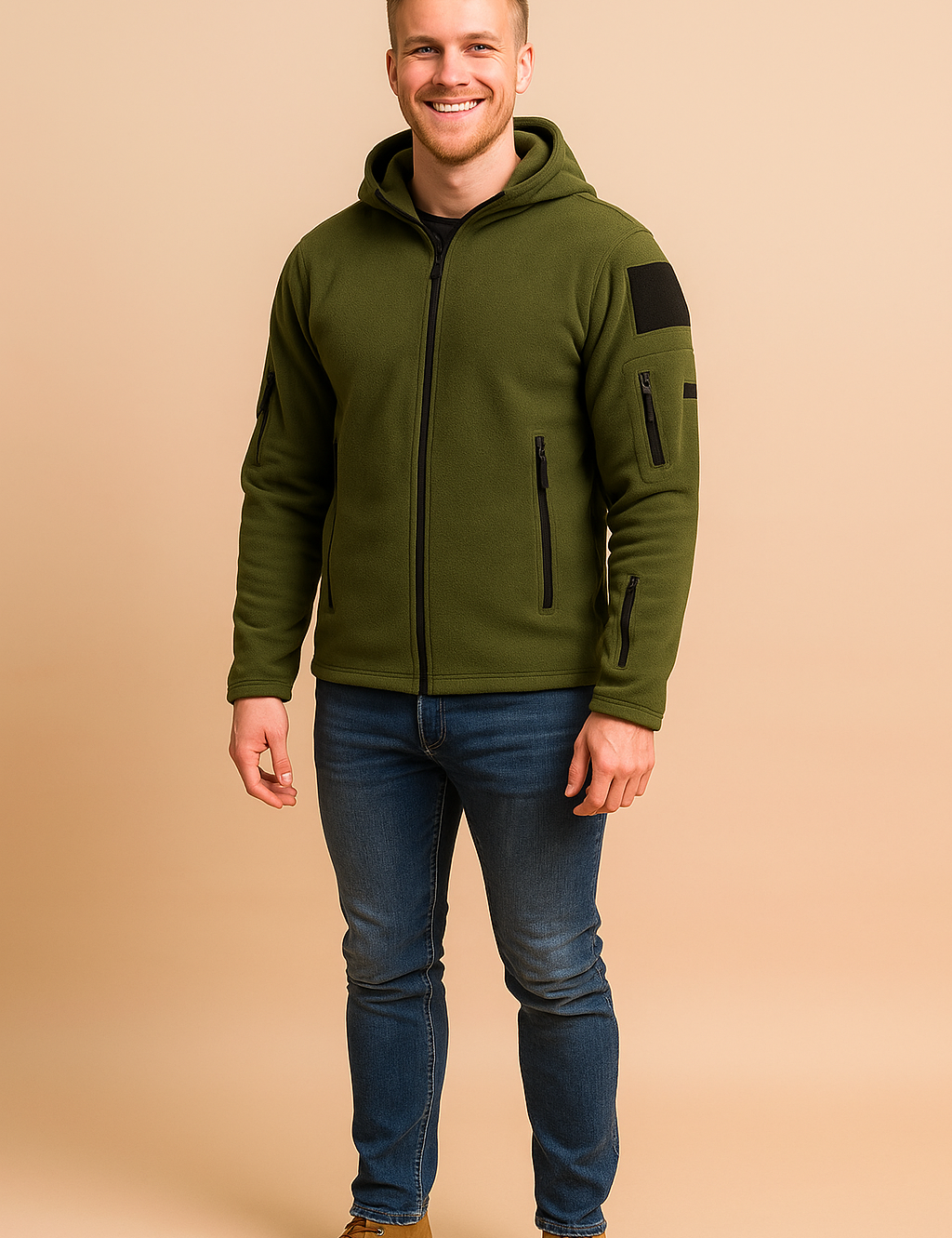 Olive green fleece zip-up jacket with multiple zippered pockets and hood, styled with slim blue jeans and tan suede boots.