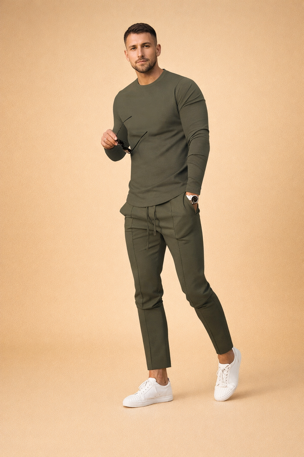 Olive green slim fit long sleeve crewneck shirt paired with matching tapered jogger pants featuring a smooth stretch fabric, clean seam detailing, adjustable drawstring waist, and white minimalist low-top sneakers for a modern athleisure look.