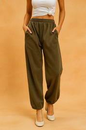 Olive green wide-leg sweatpants with a gathered elastic waist and side pockets, styled with tucked-in ankles and paired with cream heels.