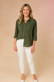 Olive green button-down linen shirt with chest pocket and rolled-up sleeves, paired with slim white pants and off-white block heel shoes.