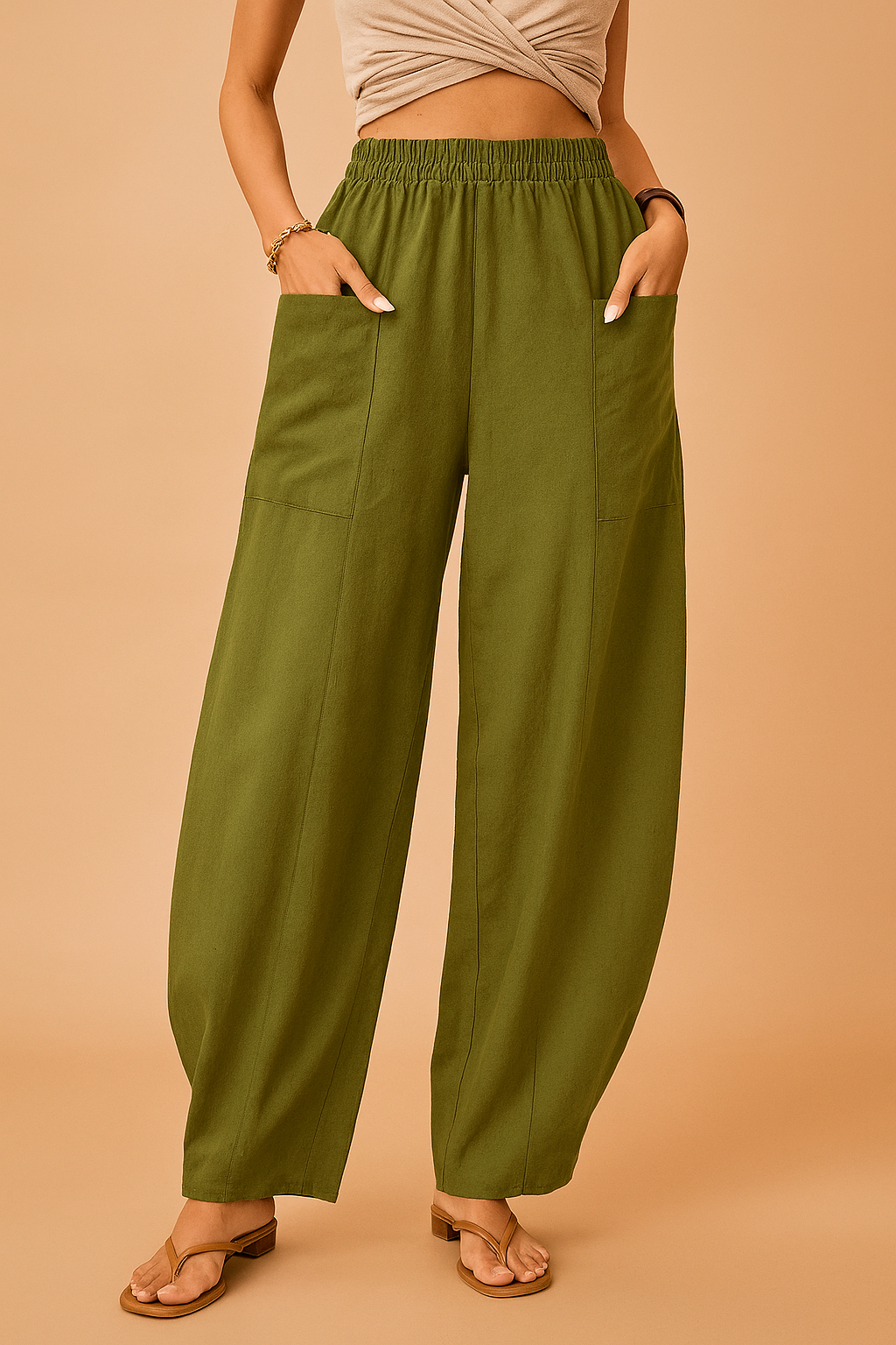 Olive green wide-leg linen pants with oversized patch pockets, relaxed drape, and visible front seams, styled with beige sandals for a casual chic look.