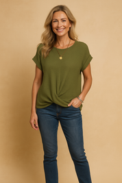 Olive green waffle-knit short-sleeve blouse with a front twist hem, featuring a relaxed fit and rolled cuffs, paired with classic mid-rise blue denim jeans.