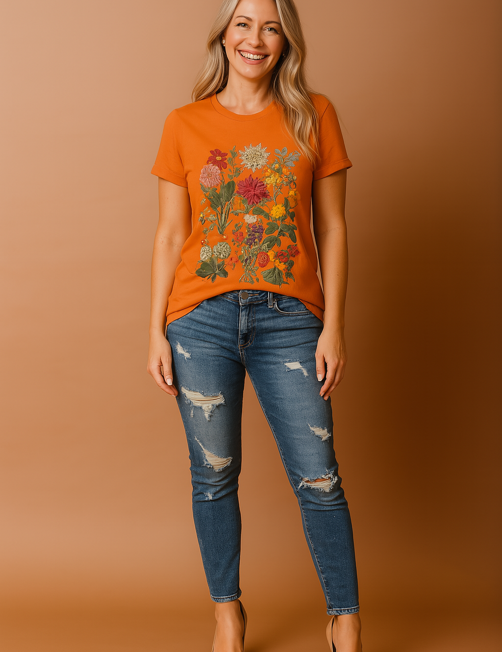 Bright orange T-shirt with intricate multicolor floral print featuring grouped blossoms in various sizes and shades, styled with distressed blue denim jeans for a bold and expressive casual look.