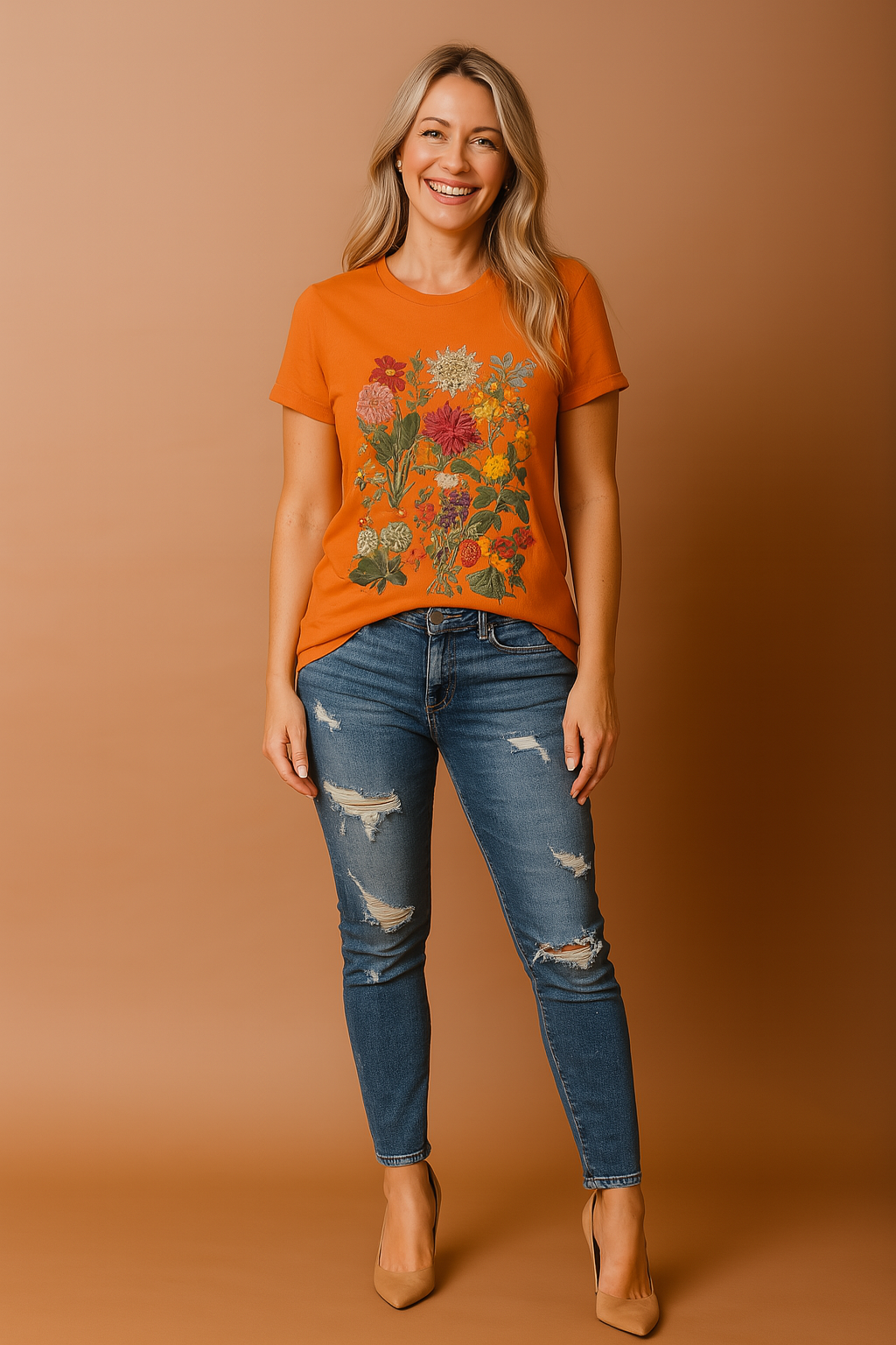 Bright orange T-shirt with intricate multicolor floral print featuring grouped blossoms in various sizes and shades, styled with distressed blue denim jeans for a bold and expressive casual look.