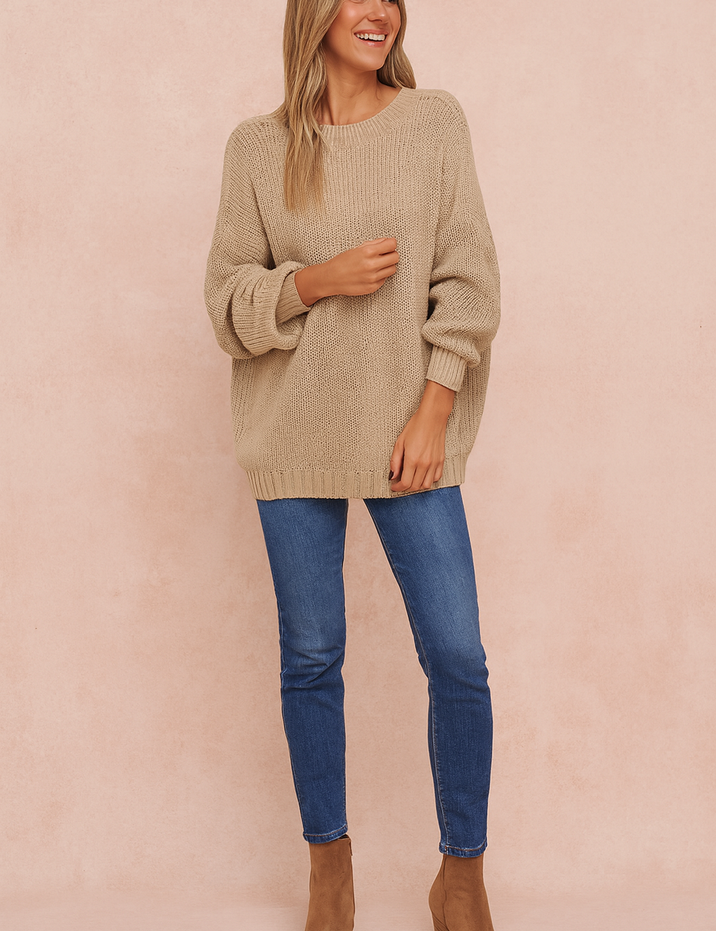  Oversized beige knit sweater with long sleeves, paired with blue skinny jeans and tan ankle boots.