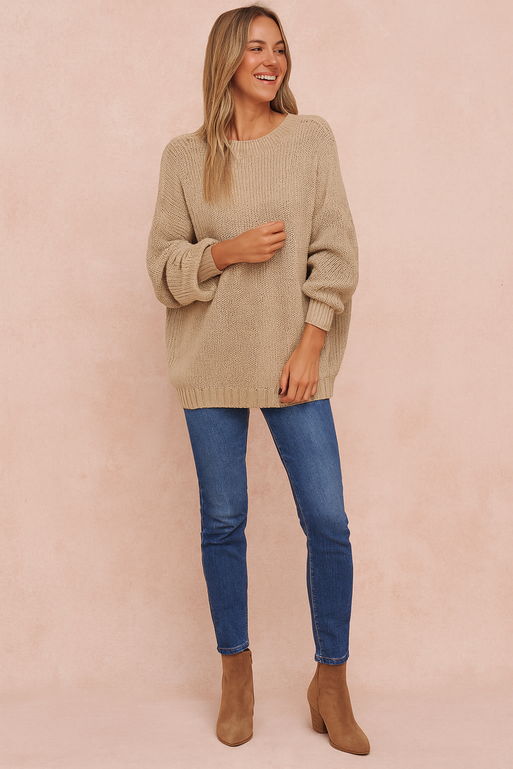  Oversized beige knit sweater with long sleeves, paired with blue skinny jeans and tan ankle boots.