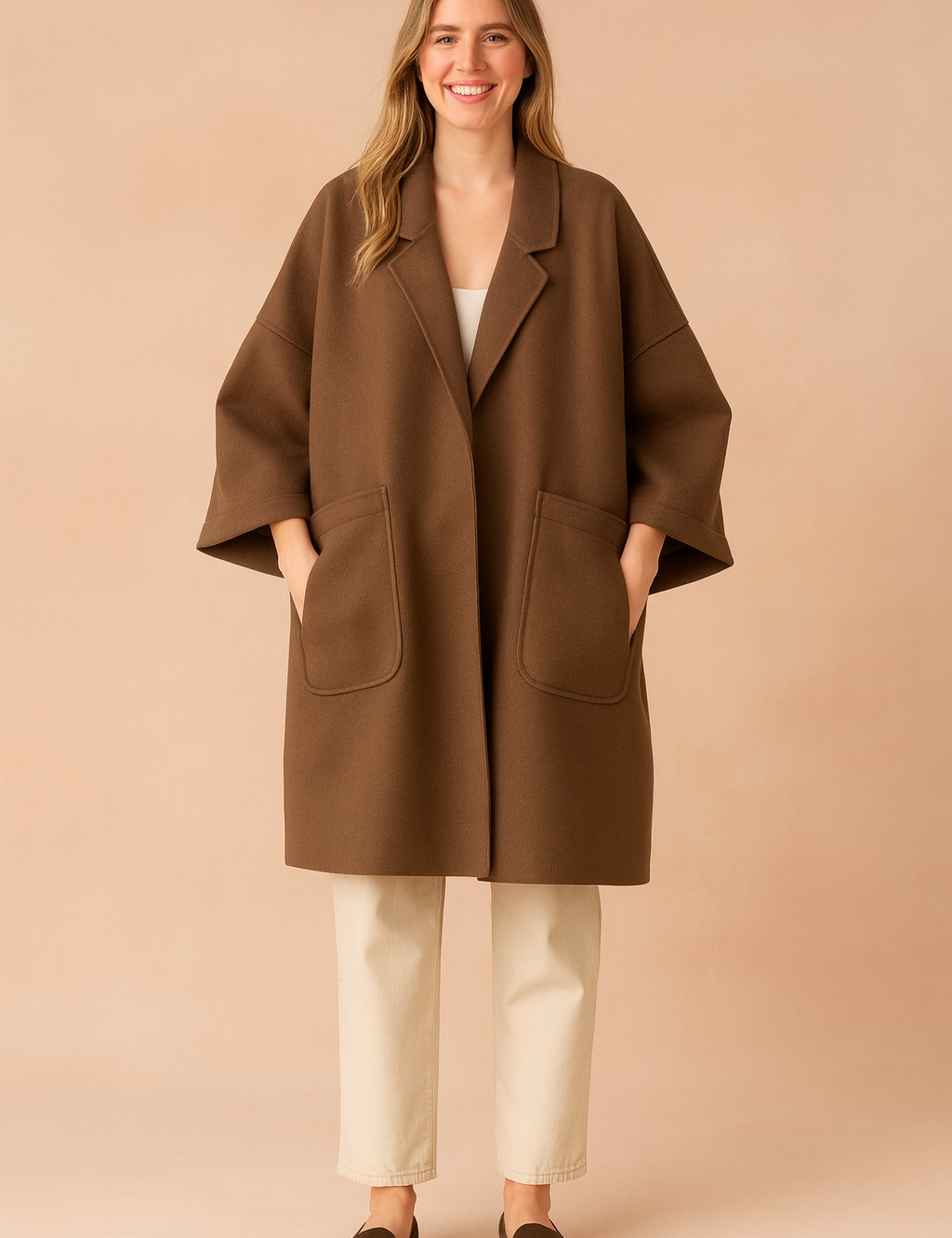 Oversized brown wool coat with wide sleeves, large front pockets, and relaxed fit, styled over light trousers and loafers for a minimalist chic look.
