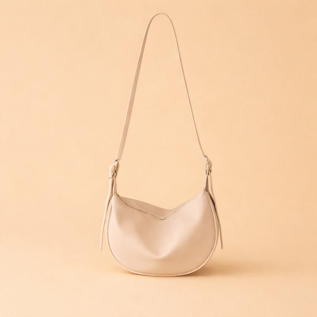 Relaxed oversized gray knit sweater styled with wide-leg black trousers and a minimalist cream crescent leather shoulder bag for a modern elevated casual look.