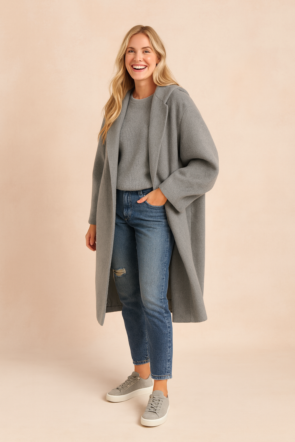 Oversized grey long wool coat with relaxed sleeves, styled with a light grey ribbed sweater, distressed blue jeans, and grey low-top sneakers.