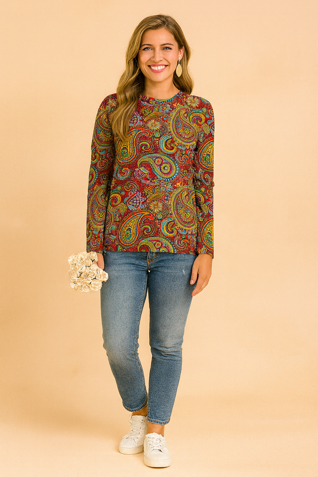 Long-sleeve paisley-print blouse in vibrant red, yellow, blue, and green tones, paired with fitted blue jeans and white sneakers.