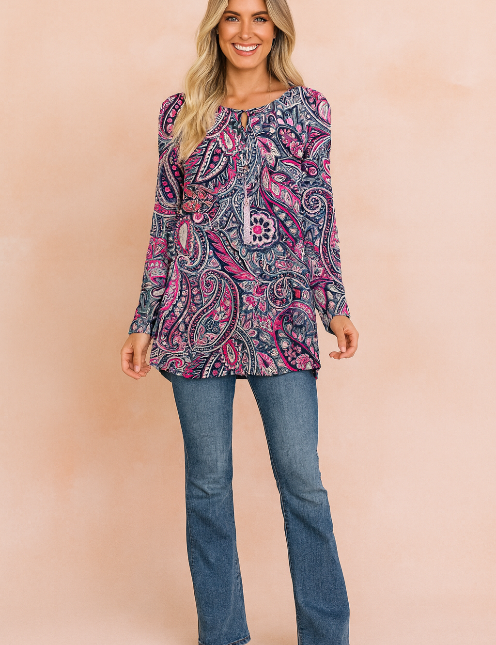 Long-sleeve tunic top with vibrant paisley print in shades of navy blue, pink, and white, paired with classic blue bootcut jeans and taupe ankle boots.