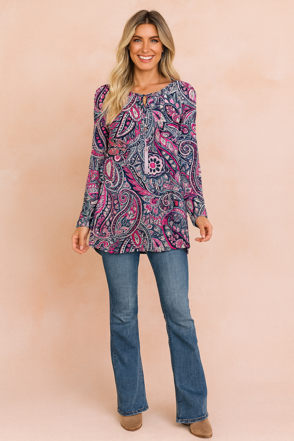 Long-sleeve tunic top with vibrant paisley print in shades of navy blue, pink, and white, paired with classic blue bootcut jeans and taupe ankle boots.