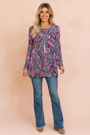 Long-sleeve tunic top with vibrant paisley print in shades of navy blue, pink, and white, paired with classic blue bootcut jeans and taupe ankle boots.