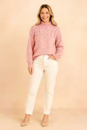 Soft pink cable-knit high-neck sweater paired with off-white straight-leg jeans and nude pointed-toe heels.