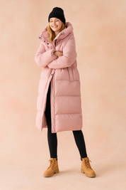 Long pastel pink puffer winter jacket with hood, full-length quilted design, snap-button closure, and side pockets.