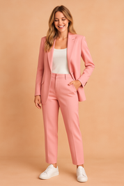 Pastel pink tailored blazer with notch lapels and matching high-waisted straight-leg trousers, styled with a fitted white tank top and white sneakers.