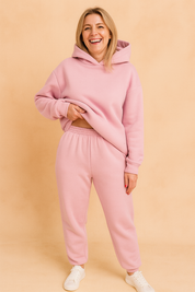 Soft pastel pink matching loungewear set consisting of an oversized hoodie and high-waisted jogger pants with gathered elastic waistband, ideal for casual or home comfort wear.