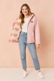 Women's pastel pink winter jacket with zip closure and soft fleece lining featuring oversized pink heart patterns, designed for warmth and style.