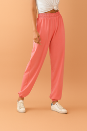 Pink high-waisted jogger pants with an elastic waistband and cuffed hems, styled with white lace-up sneakers.