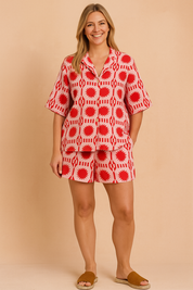 Playful pink and red geometric print co-ord set with button-down shirt and drawstring shorts, styled with flat nude sandals for a vibrant summer look.