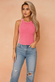 Women's pink acid-wash ribbed tank top with raw edge detail, styled with high-waisted distressed light-wash denim jeans — casual summer fashion essential.