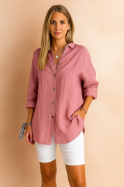 Stylish woman wearing a button-up blouse with rolled sleeves paired with white shorts