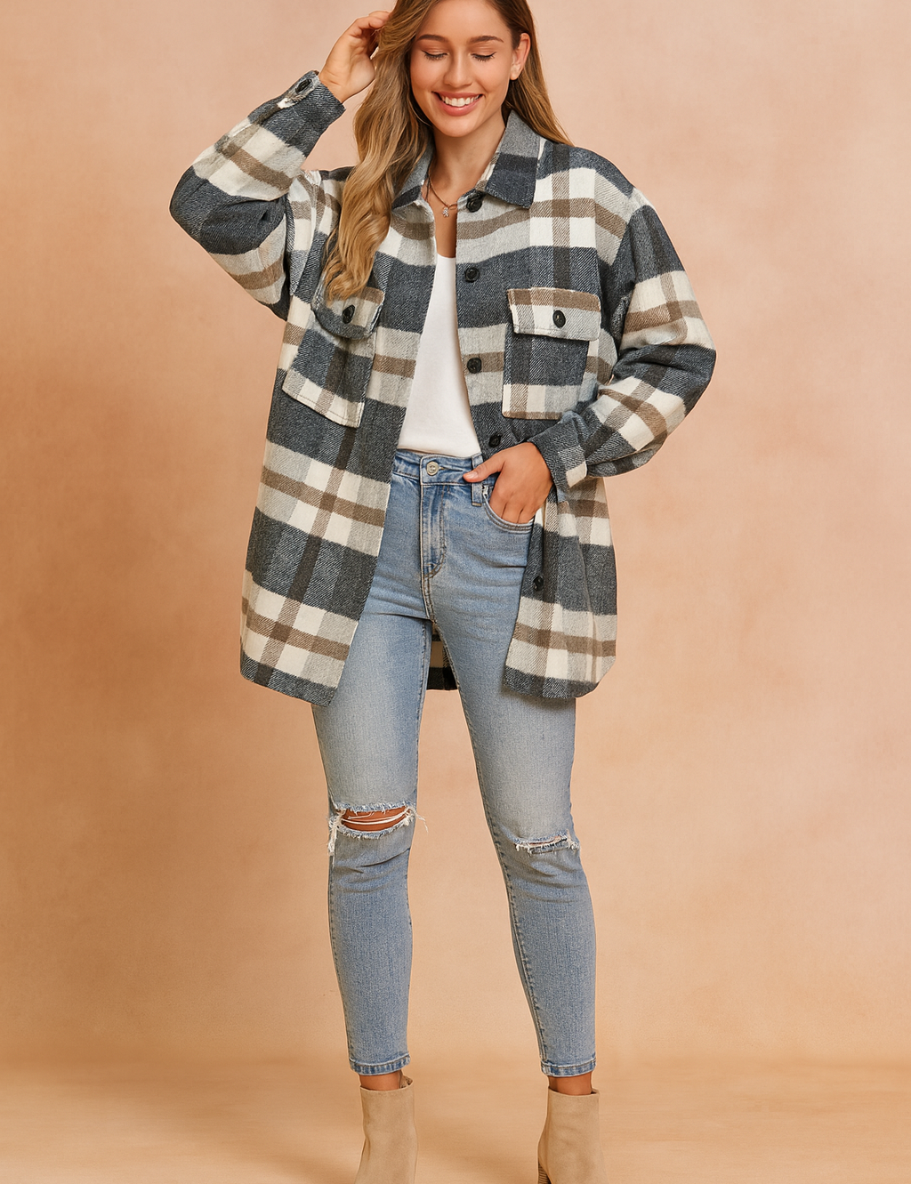 Oversized plaid shacket in grey, white, and brown check pattern, featuring front button closure, dual chest flap pockets with buttons, and a relaxed longline cut. Styled over a white top with distressed light-wash skinny jeans and beige ankle boots for a casual-chic layered look.