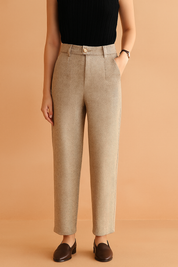 Khaki herringbone high-waisted tailored trousers with pleats, belt loops, and a single wood-grain button, styled with dark brown loafers.
