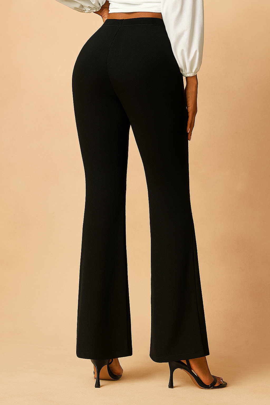 Black high-waisted flare pants with a smooth finish and ankle-length cut, styled with a white puff-sleeve blouse and heeled sandals.