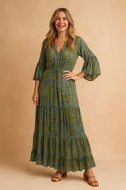 Bohemian-style long sleeve maxi dress with tiered skirt and plunging neckline, featuring a green and blue paisley print with subtle tribal-inspired motifs, crafted in a lightweight flowy fabric.
