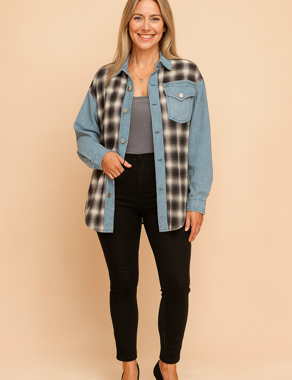 Two-tone oversized button-up shacket combining black-and-white plaid flannel with light blue denim panels, featuring a single front flap pocket, full sleeves, and metal snap buttons, styled over a ribbed gray crop top and paired with high-waisted black skinny jeans.