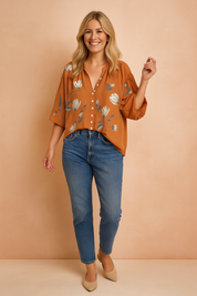Burnt orange floral button-down blouse with wide half sleeves, soft V-neckline, and an airy fit, featuring a scattered pattern of ivory and gray tulip blooms with muted blue-green leaves.