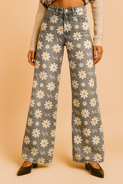 High-waisted wide-leg jeans in faded gray with a white daisy floral print and light distressing, styled with front pockets, belt loops, and black heeled shoes.