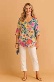 Loose-fit floral V-neck blouse with elbow-length sleeves, featuring a vivid multicolor print of pink, red, blue, and yellow flowers with green and navy leaves on a light pastel base.