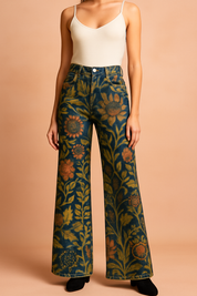 Wide-leg high-waisted jeans featuring a vivid vintage floral tapestry print in deep indigo, muted mustard, and warm terracotta tones, styled with a button fly and front pocket seams.
