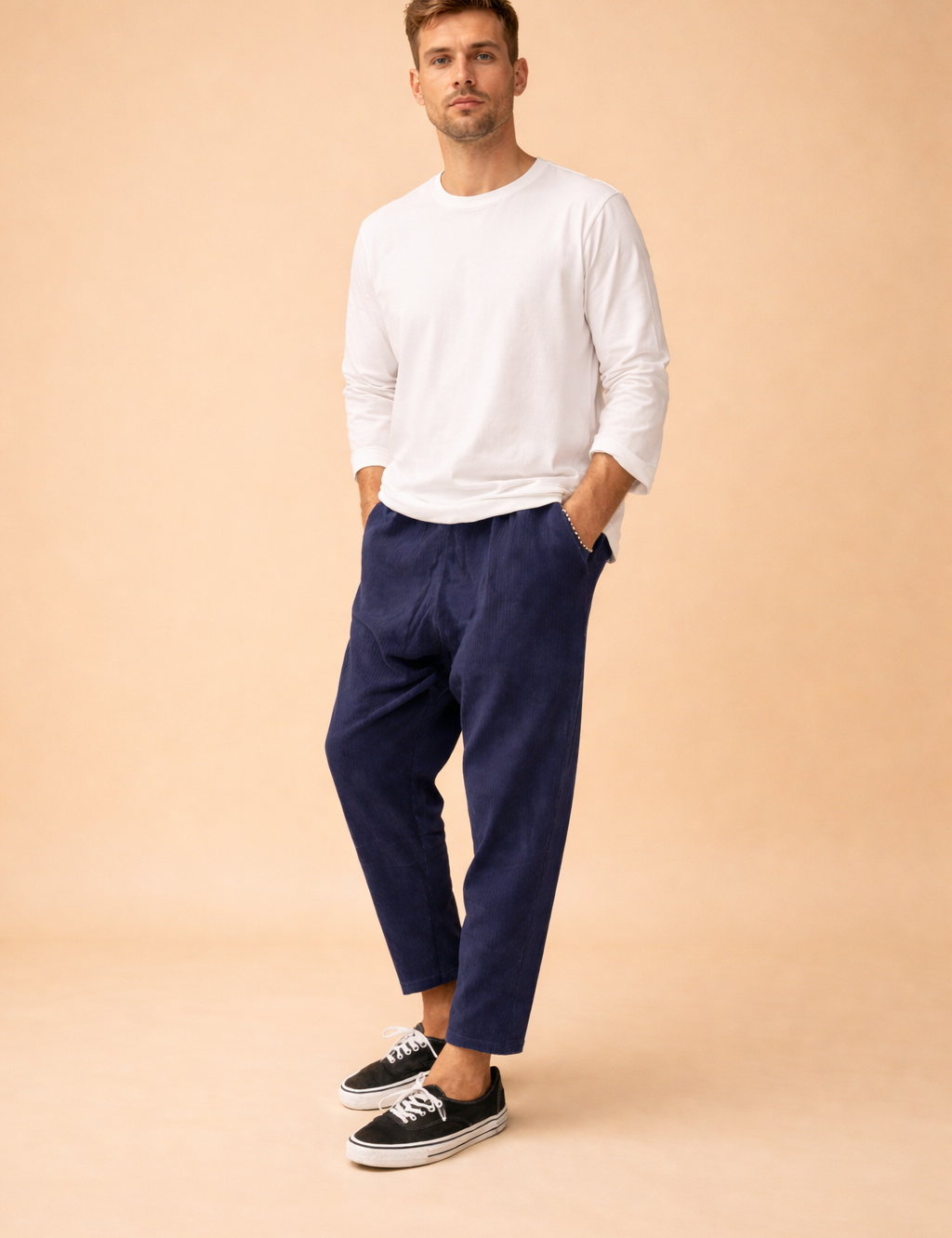 Relaxed-fit ankle-length men’s trousers with a straight leg cut, clean waistband, subtle vertical texture, and minimalist finish, styled with a long-sleeve top and low-profile lace-up sneakers for a modern casual look.