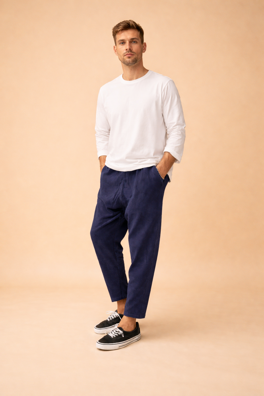 Relaxed-fit ankle-length men’s trousers with a straight leg cut, clean waistband, subtle vertical texture, and minimalist finish, styled with a long-sleeve top and low-profile lace-up sneakers for a modern casual look.