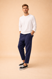Relaxed-fit ankle-length men’s trousers with a straight leg cut, clean waistband, subtle vertical texture, and minimalist finish, styled with a long-sleeve top and low-profile lace-up sneakers for a modern casual look.