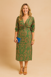 Green midi dress with three-quarter sleeves, featuring an intricate rust-colored paisley pattern throughout, a center front twist detail at the bust, a defined waistband, and a straight hemline that falls below the knee.