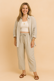 Relaxed-fit two-piece loungewear set featuring a long-sleeve button-up shirt and matching drawstring pants, crafted in a soft, natural linen-look fabric with a subtle beige weave pattern and clean tailoring for an effortlessly casual-chic look.