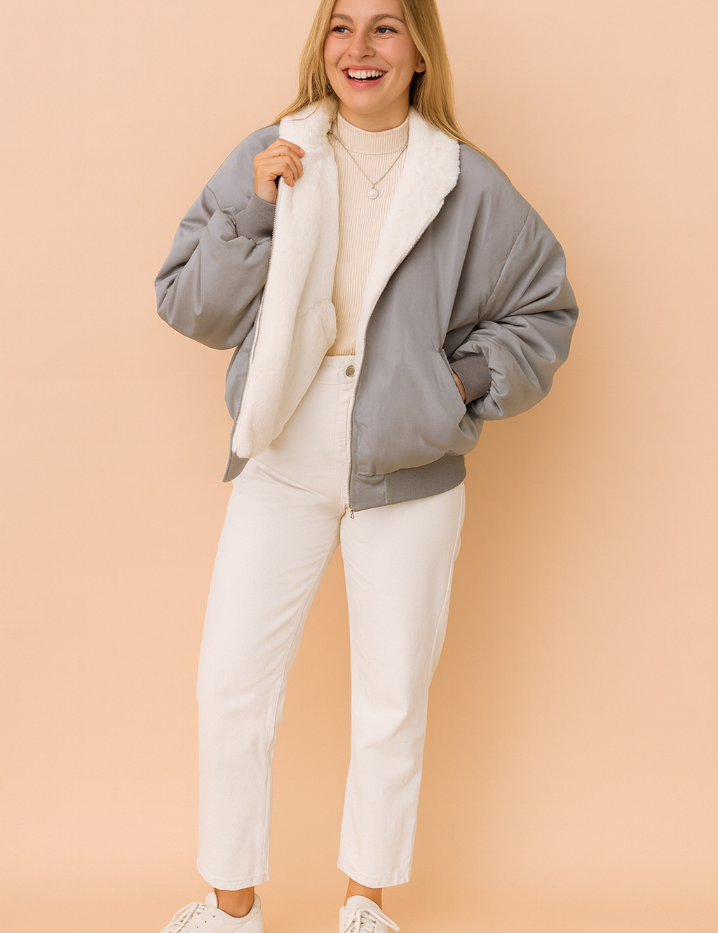 Gray bomber jacket with plush white fleece lining, styled over a beige ribbed turtleneck sweater and paired with white straight-leg pants and casual white sneakers.