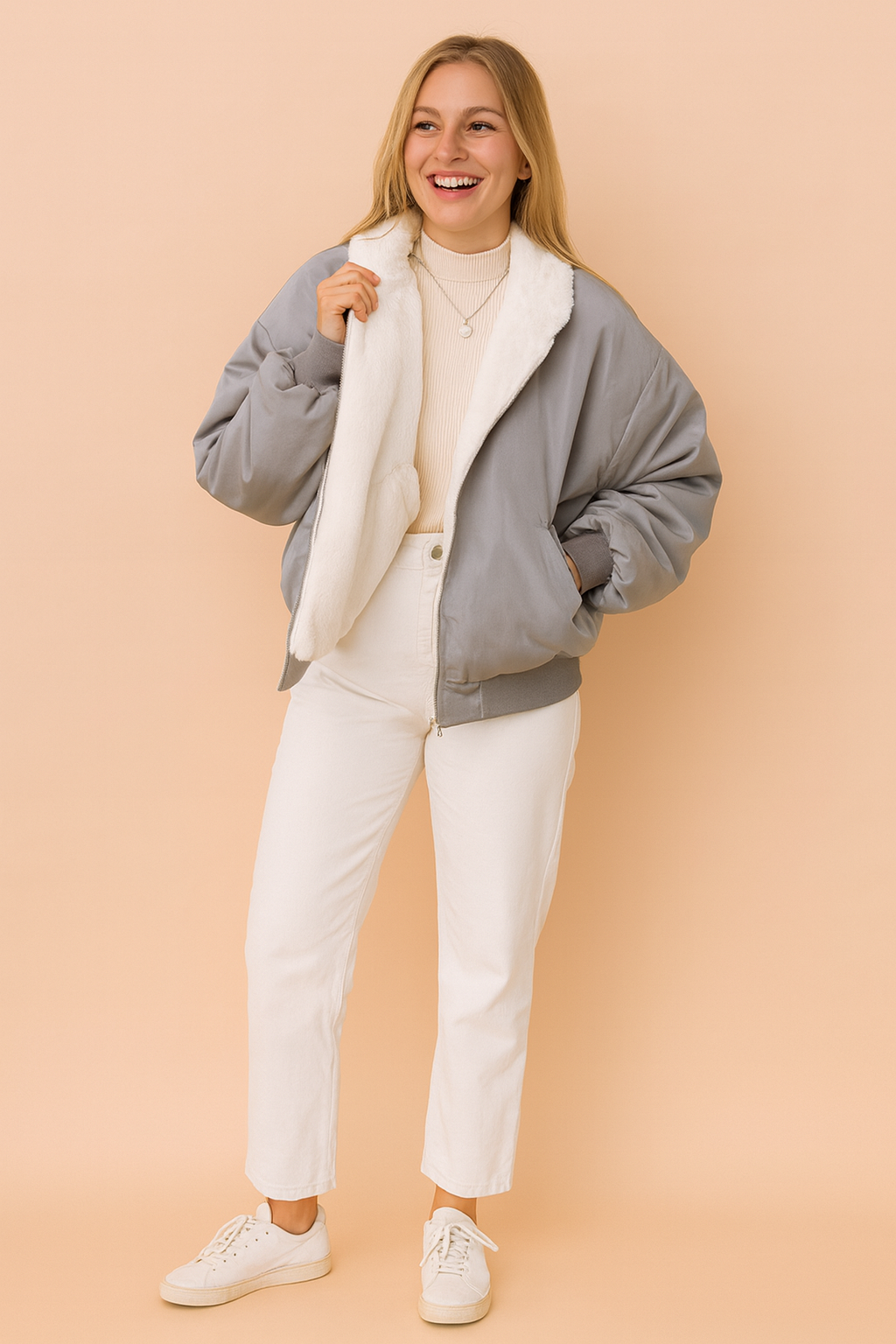 Gray bomber jacket with plush white fleece lining, styled over a beige ribbed turtleneck sweater and paired with white straight-leg pants and casual white sneakers.