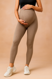 Taupe high-waisted maternity leggings with a smooth, body-hugging fit and ankle-length cut, styled with white chunky sneakers.